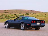 VET 01 RK0818 01
1984 Chevrolet Corvette Coupe Black 3/4 Rear View On Pavement By Hill Blue Sky
