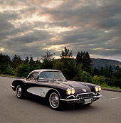 VET 02 RK0106 01
1959 Chevrolet Corvette Black Convertible Roadster And White 3/4 Front View On Pavement Trees Background