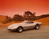 VET 05 RK0115 04
1975 Chevrolet Corvette Stingray Convertible Silver 3/4 Side View On Pavement By Hills And Trees Filtered