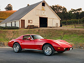 VET 05 RK0162 01
1977 Chevrolet Corvette Coupe Red 3/4 Front View On Pavement By Barn