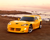 VIP 01 RK0150 03
1996 Dodge Hennessey Viper Venom 650R Yellow 3/4 Front View On Sand By Rocks And Ocean Headlights On At Dusk